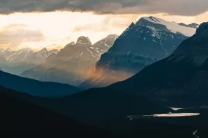 Mountains emerge from the shadows under a dramatic sky.