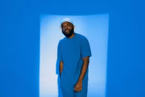 A man poses in a blue, monochromatic setting.