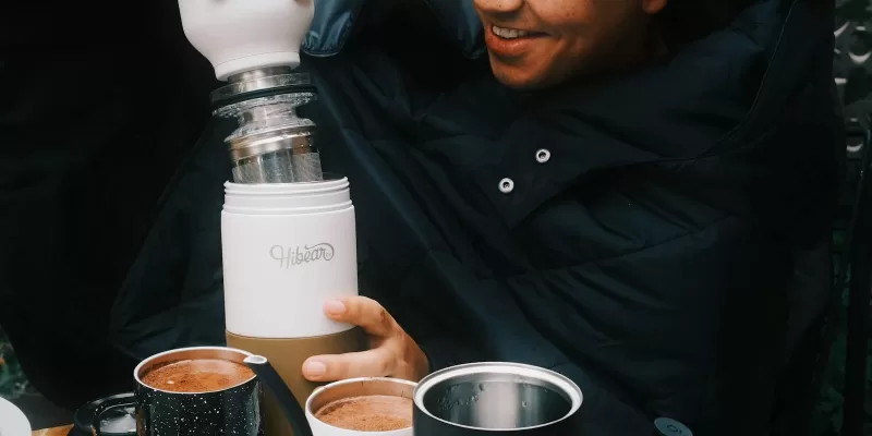 Man preparing coffee with portable coffee maker outdoors